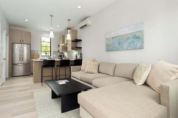 This open-concept living room offers the perfect blend of comfort and style, complete with a large sofa and natural light galore.