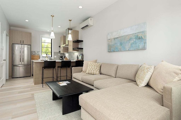 This open-concept living room offers the perfect blend of comfort and style, complete with a large sofa and natural light galore.