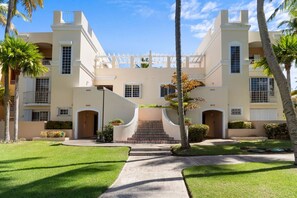 This stunning apartment building features a modern architectural design, complemented by lush palm trees that enhance its tropical appeal.