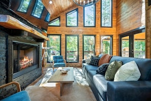 Relax on the plush sofa and take in the view through expansive windows, or cozy up with your favorite show on the smart TV beside the indoor fireplace — comfort and charm at every turn.