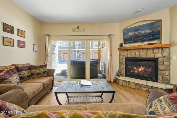 Living room with large TV, queen sleeper and walk-out access to private hot tub