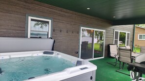 Outdoor covered dining area with gas grill and a 6 person jacuzzi with a view.