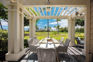 Elegant outdoor dining under a shaded pergola with tropical garden views and a glimpse of the ocean