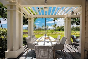 Elegant outdoor dining under a shaded pergola with tropical garden views and a glimpse of the ocean
