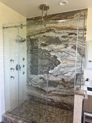 Master bathroom with rain shower, glass enclosure, and onyx wall