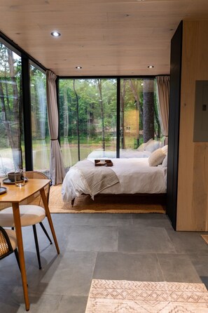 Wake up wrapped in comfort with nature just beyond the glass—our plush queen bed is made for slow mornings and starry nights.