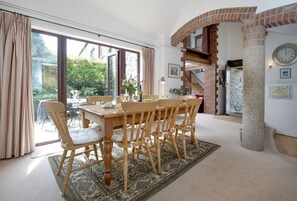 The Linhay, Noss Mayo. Ground Floor: Open-plan kitchen and dining area, with high ceilings, exposed brickwork and concrete pillars