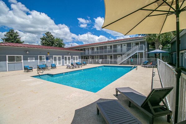 Enjoy the sunny days by the shared pool, surrounded by lounge chairs and a backdrop of blue skies and fluffy clouds.