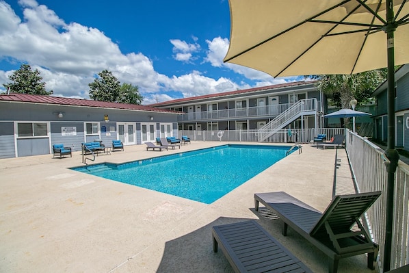 Enjoy the sunny days by the shared pool, surrounded by lounge chairs and a backdrop of blue skies and fluffy clouds.