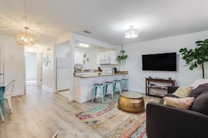 Step into this cozy living space featuring an open layout with stylish décor, a smart TV, and easy access to the full kitchen.
