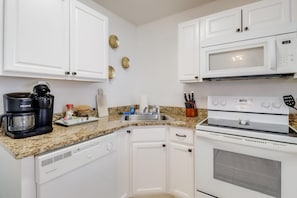 A modern kitchen equipped with a dishwasher, microwave, and coffee maker, ideal for preparing meals during your stay in Biloxi.