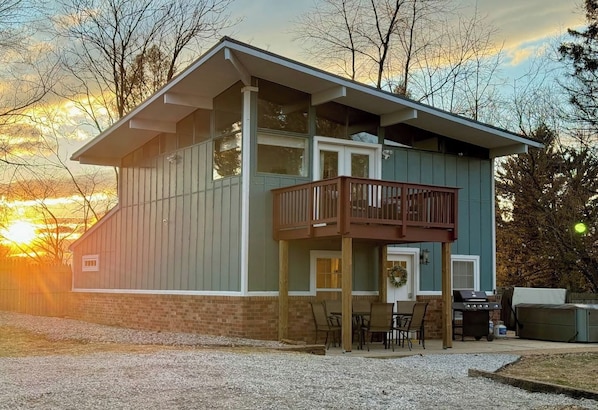 Asymmetrical roof line with large windows in the second floor with a balcony, perfect to enjoy the mountain view peeking out from the treeline.