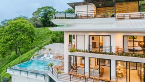This multi-level home glows at twilight with lit terraces, a sparkling infinity pool, and outdoor loungers.