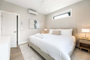 Unwind in this beautifully appointed bedroom with a king bed, cozy linens, and a stylish area rug. The room includes dual nightstands with lamps, a ceiling fan, and a sleek dresser topped with a wall-mounted TV for your entertainment.