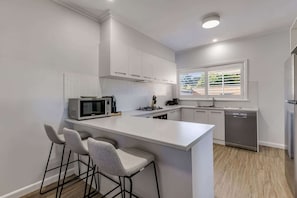 Fully-equipped kitchen with stove, oven, toaster, kettle, dishwasher, pod coffee machine and more.