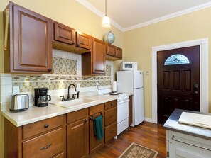 Kitchen area with Keurig coffee maker, microwave, refrigerator, and basic cookware, dishes and utensils.