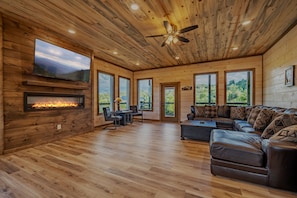 Large sectional and seating area with electric fireplace and 65 inch smart TV.