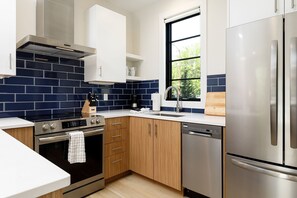 Cook in style with this modern kitchen featuring stainless steel appliances and a bold blue backsplash