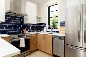 Cook in style with this modern kitchen featuring stainless steel appliances and a bold blue backsplash