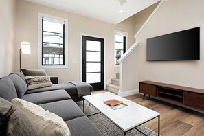 Relax in this modern living room with a cozy sectional, stylish decor, and natural light.