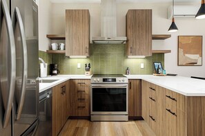 Fully equipped kitchen with a sleek design, green tile backsplash, and all the essentials.