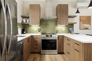 Fully equipped kitchen with a sleek design, green tile backsplash, and all the essentials.