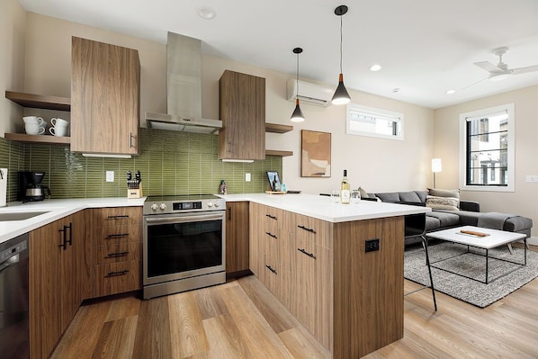 Enjoy the charm of this contemporary kitchen with open shelving, pendant lighting, and stainless steel appliances.