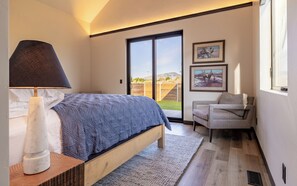Spacious primary bedroom suite with plush king bed, access to the outdoor courtyard and vaulted ceilings.