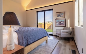 Spacious primary bedroom suite with plush king bed, access to the outdoor courtyard and vaulted ceilings.