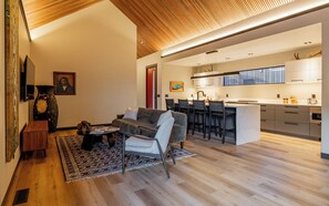 Open-concept living, dining, and kitchen area featuring stunning vaulted ceilings with custom linear wood detailing