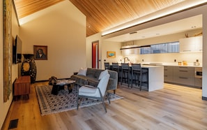 Open-concept living, dining, and kitchen area featuring stunning vaulted ceilings with custom linear wood detailing