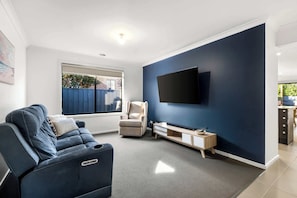 Living room with flat screen TV and recliner chairs.