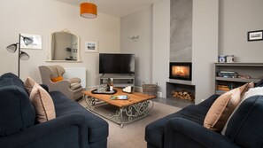 Cambridge House - sitting room with two large sofas, armchair, wood burning stove and large smart TV