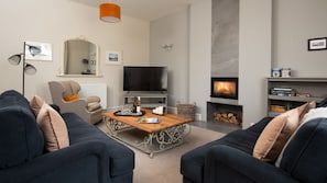 Cambridge House - sitting room with two large sofas, armchair, wood burning stove and large smart TV