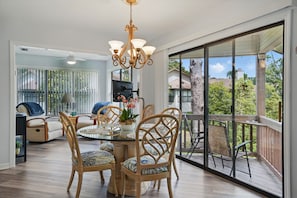Dining Area with Screened Porch Access – 308 Harbour Oaks - Slide open the glass doors and let the outdoors join you for breakfast. This shot connects the dining table, porch, and sitting nook into one open, sunlit space that feels like a vacation even if you're just eating leftovers.