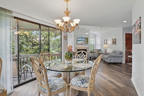 Dining Area with Porch View – 308 Harbour Oaks - Meals, game nights, or just lingering with wine—this glass-topped table sits right beside the screened porch and wooded backdrop. It’s the kind of light-drenched spot where even cereal feels like vacation on St. Simons Island.