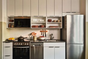 White cabinets with stove, sink, and plates on open shelves