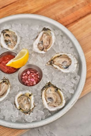 Plate of oysters on ice with lemon and sauces