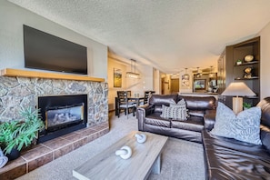 Cozy up in this inviting living room with plush leather seating, a warm stone fireplace, and stunning mountain views right from your private balcony.