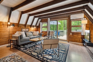 The main living area! There is a smart tv with cable and the ability to login to your own streaming platforms. There is also air conditioning! Access to the deck and hot tub is right out the patio door. Black out curtains throughout