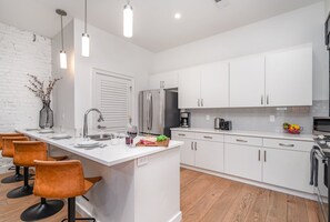 Fully equipped kitchen featuring stainless steel appliances, open counter space, and bar seating for 4 guests.