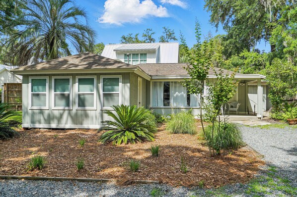 Front Exterior – Walk to Pier, Ice Cream, and Live Music - Just steps from Frosty’s Grill, Village Inn & Pub, and the Pier, this Magnolia Avenue vacation rental brings you as close to downtown St. Simons as it gets. The charming front exterior is tucked under mossy oaks and palm fronds, with gravel parking for 4+, a covered porch, and plenty of room for your golf cart—or your boat.