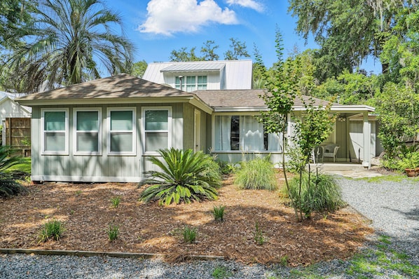 Front Exterior – Walk to Pier, Ice Cream, and Live Music - Just steps from Frosty’s Grill, Village Inn & Pub, and the Pier, this Magnolia Avenue vacation rental brings you as close to downtown St. Simons as it gets. The charming front exterior is tucked under mossy oaks and palm fronds, with gravel parking for 4+, a covered porch, and plenty of room for your golf cart—or your boat.