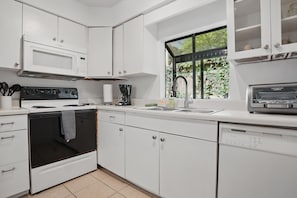 Kitchen – Bright, Efficient, and Ready to Roll - The kitchen at 412 Magnolia Avenue keeps it classic. Bright white cabinetry, a full-size fridge, and a regular drip coffee maker mean everything you need is within reach—without trying too hard. Cook, reheat, or just stock the fridge with leftovers from Iguanas, Porch, or Georgia Sea Grill (all a short walk away).