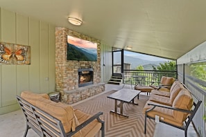 Enjoy mountain breezes on this covered patio complete with a cozy fireplace, Large TV, cushioned seating, and scenic views.