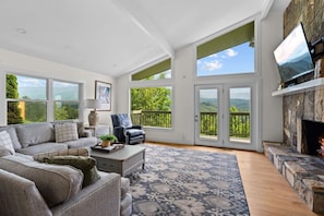Gather with loved ones in this airy living room, where soaring ceilings, a stone fireplace, and panoramic windows frame the Smokies in every direction.