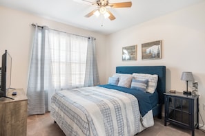 Lovely guest bedroom with a queen-sized bed, a TV, and clothing storage.