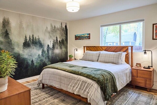 Spacious primary bedroom with King size mattress and forest wallpaper.