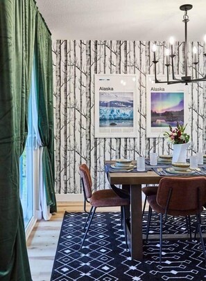 Stylish 6 person dining room with birch tree wallpaper and art highlighting Alaska.