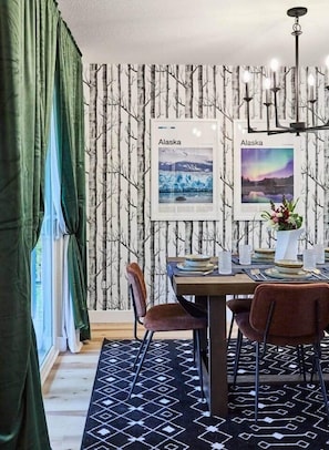 Stylish 6 person dining room with birch tree wallpaper and art highlighting Alaska.